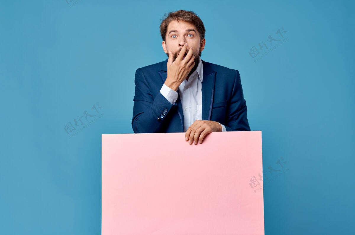 男人商人拿着蓝色背景的粉红色宣传广告牌标志牌小伙子人