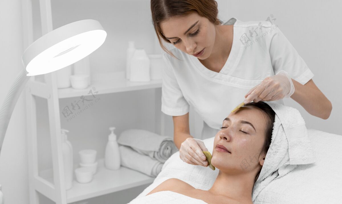 面部护理美容师为女性客户做美容常规灯化妆品女人