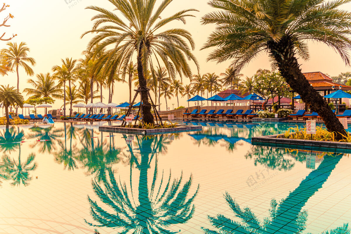 蓝色美丽的棕榈树与伞椅游泳池豪华酒店度假村日出泰晤士报.假日还有度假的概念无限度假光