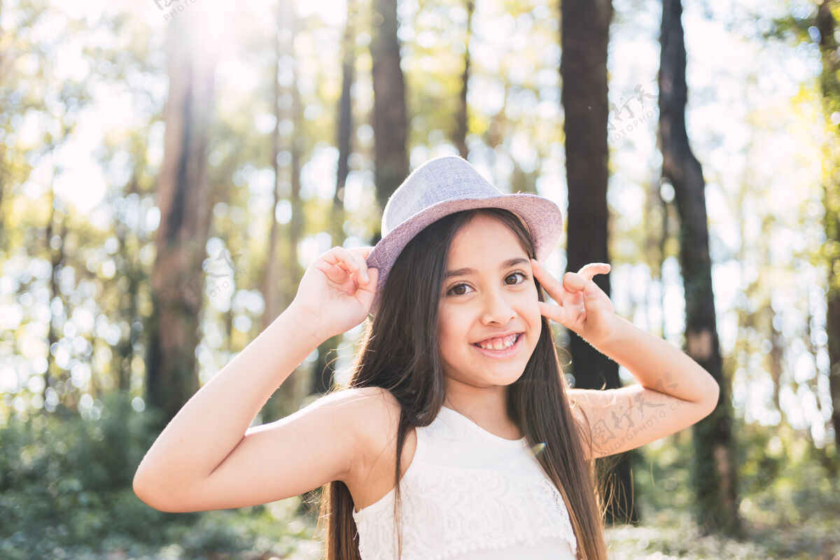 天一个可爱的女孩快乐微笑的肖像-一个美丽的长发女孩戴着帽子在户外快乐花园儿童时尚