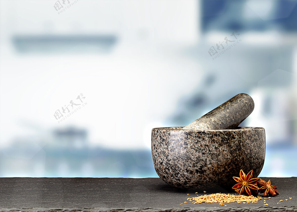 杵在模糊的厨房前面的桌子上放着花岗岩砂浆和香料香料室内模糊背景
