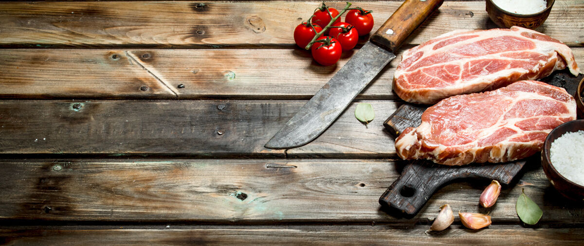 猪肉生猪排配番茄香料木制背景准备牛排食物