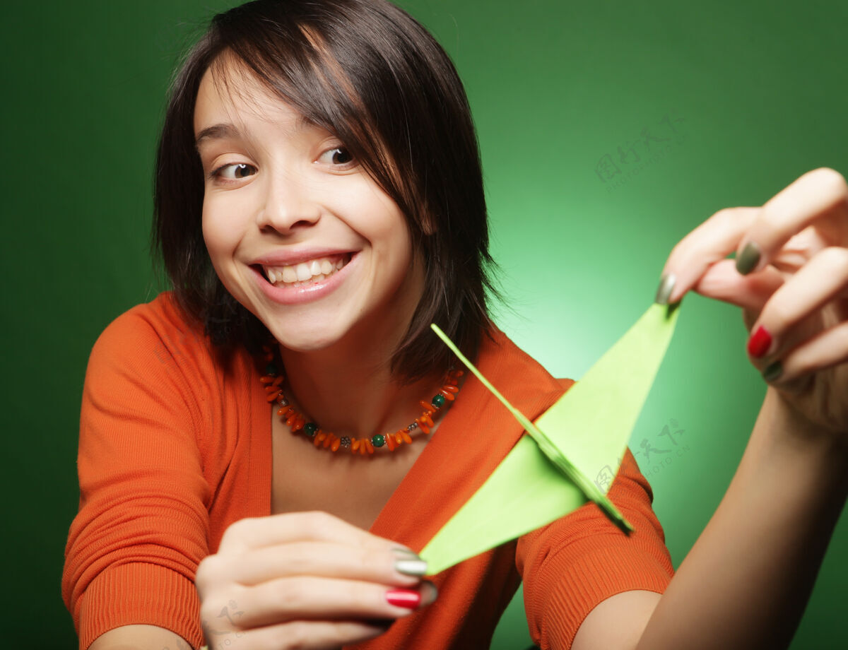 可爱一个年轻的表情女人 在绿色的墙壁上带着纸鸟兴奋头发人类