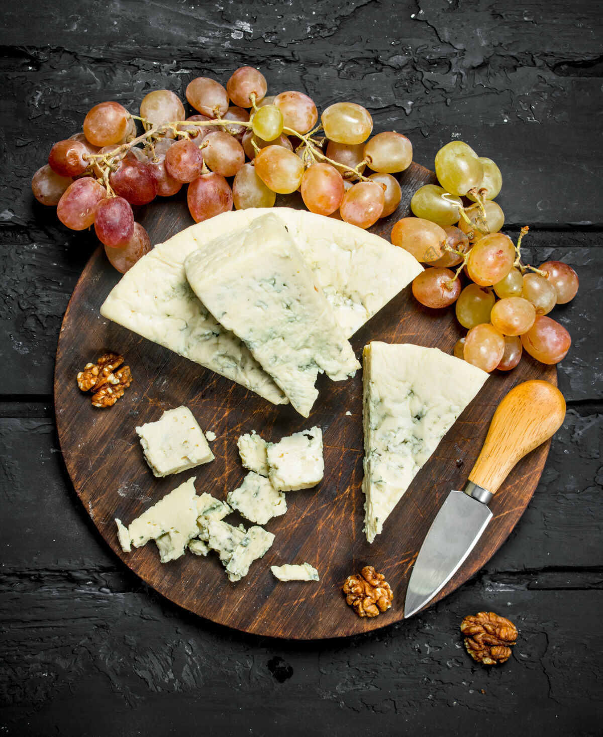 软蓝色奶酪放在木板上葡萄.on黑色乡村背景刀牛奶块