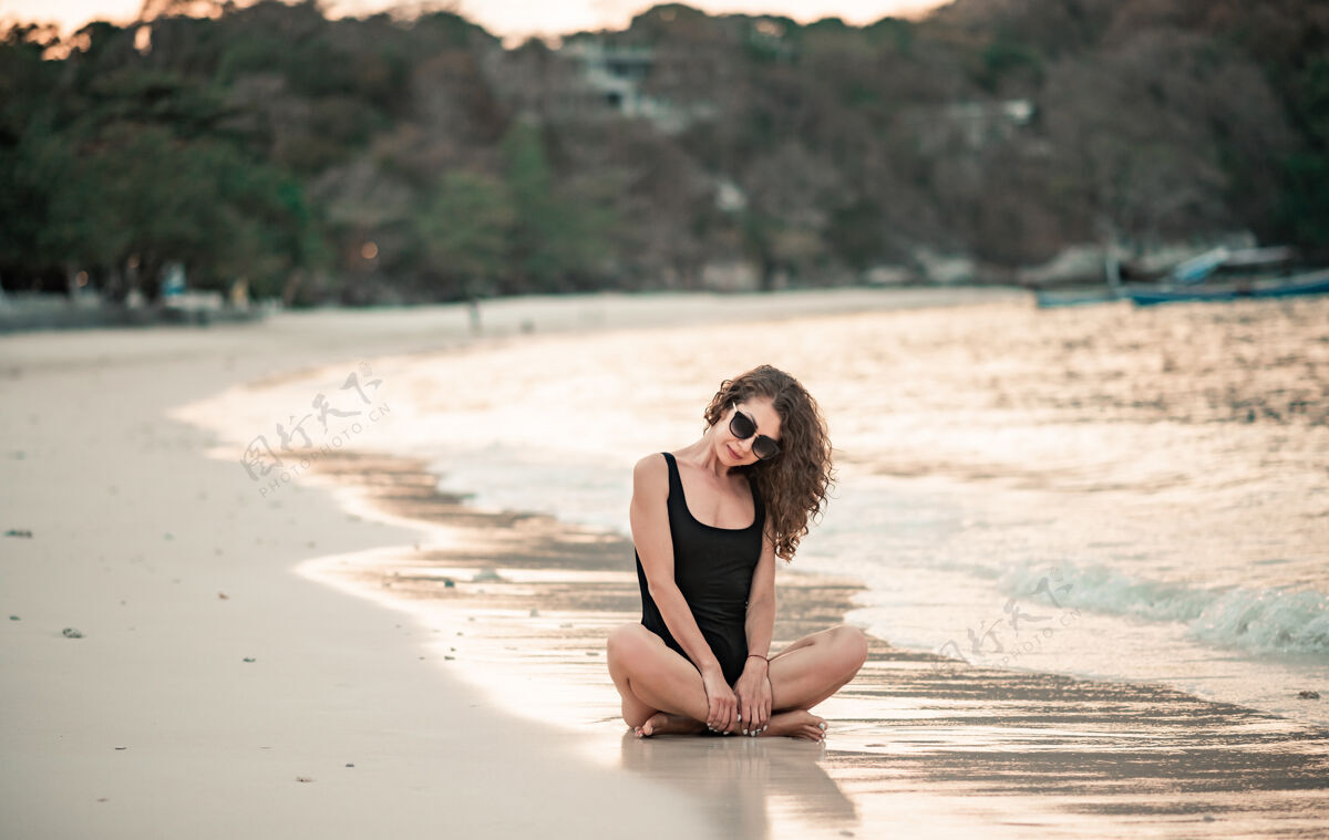 模特优雅的女人 留着长长的头发 穿着黑色豪华比基尼 在沙滩上放松海滩夏天假期海边季节阳光