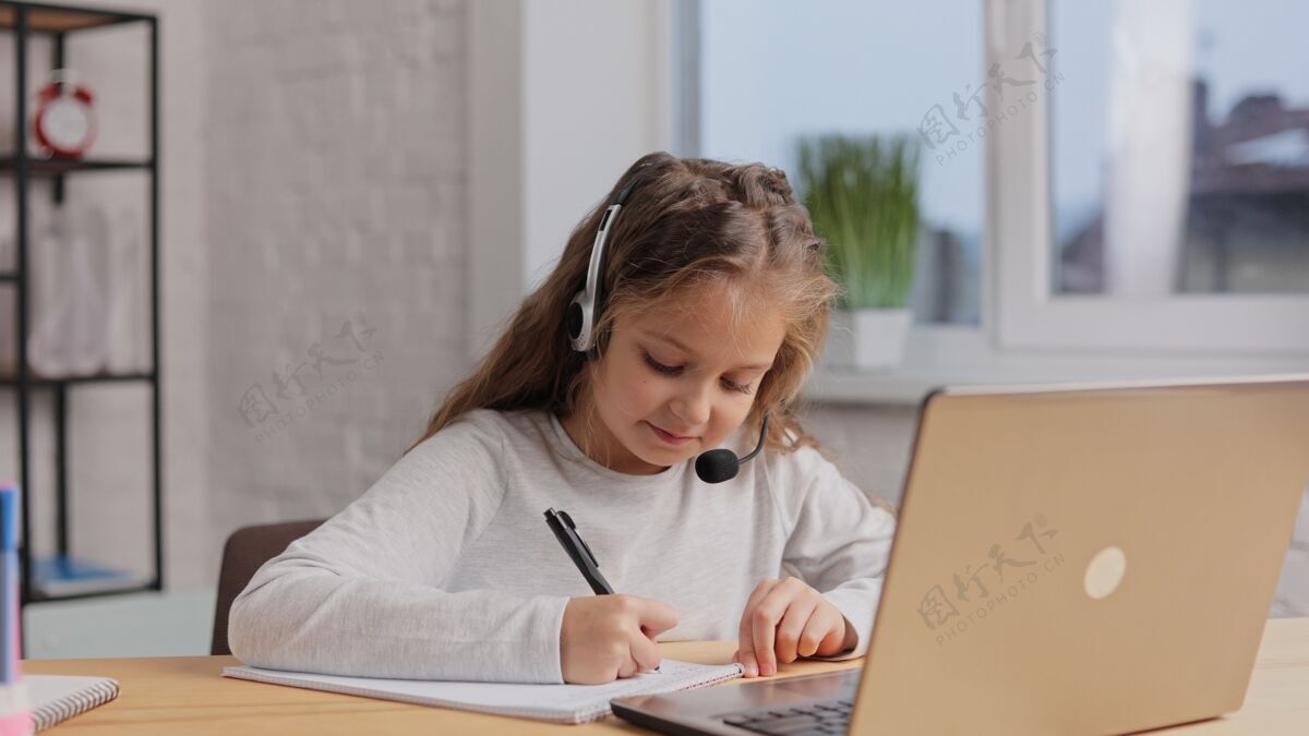 留在家里女生在耳机里有在线课 视频通话用老师可爱小学女生在家用笔记本电脑学习远程教育数字学生