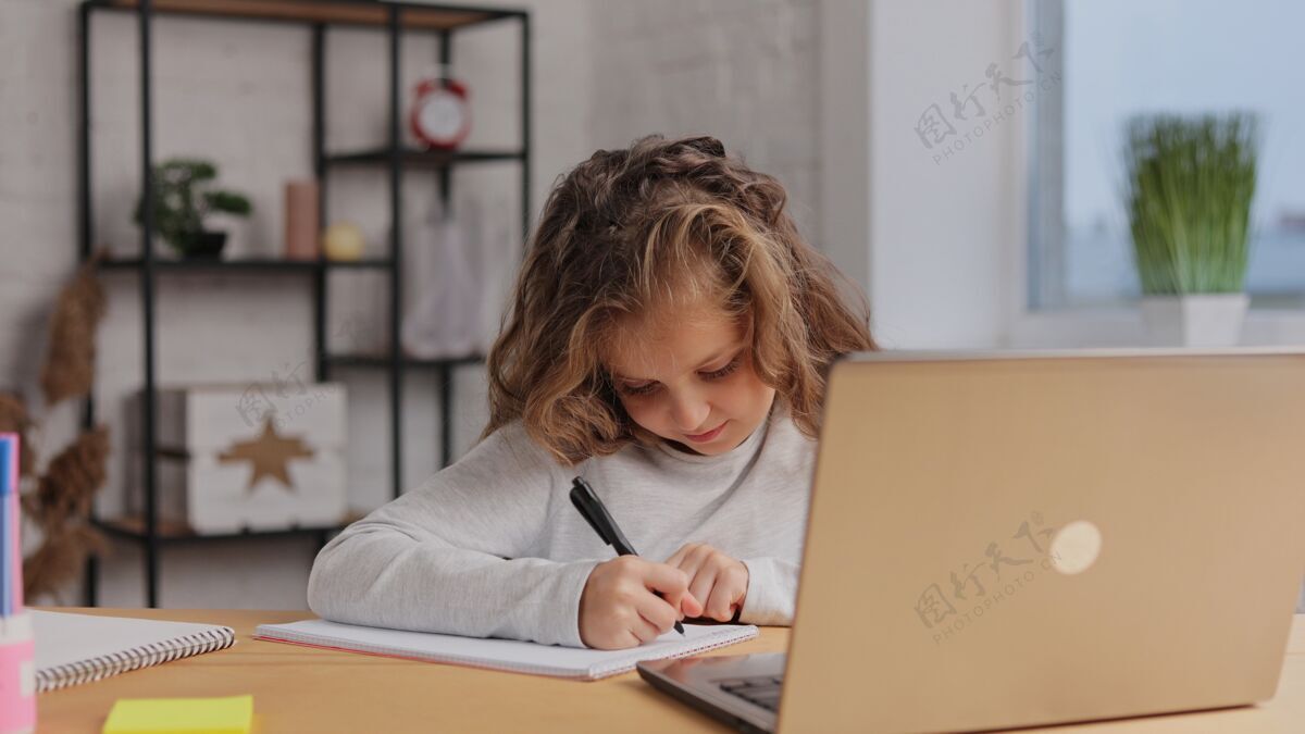 学生可爱的小学生在家用笔记本电脑学习电脑女学生有网络课 写练习本 做作业老师家庭作业学习