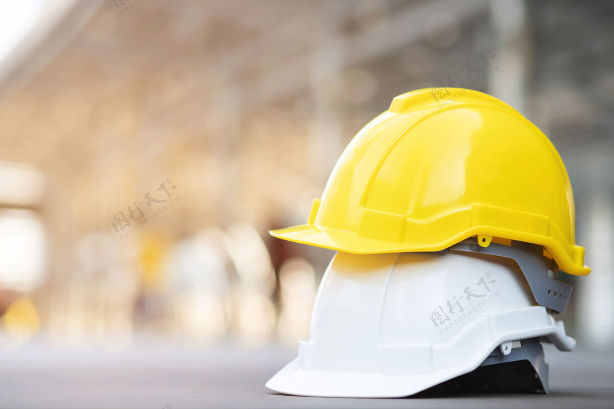 帽子黄色和白色的安全帽 在工程施工现场的混凝土地面上的建筑物阳光.头盔作为工程师或工人概念安全第一硬工程师危险
