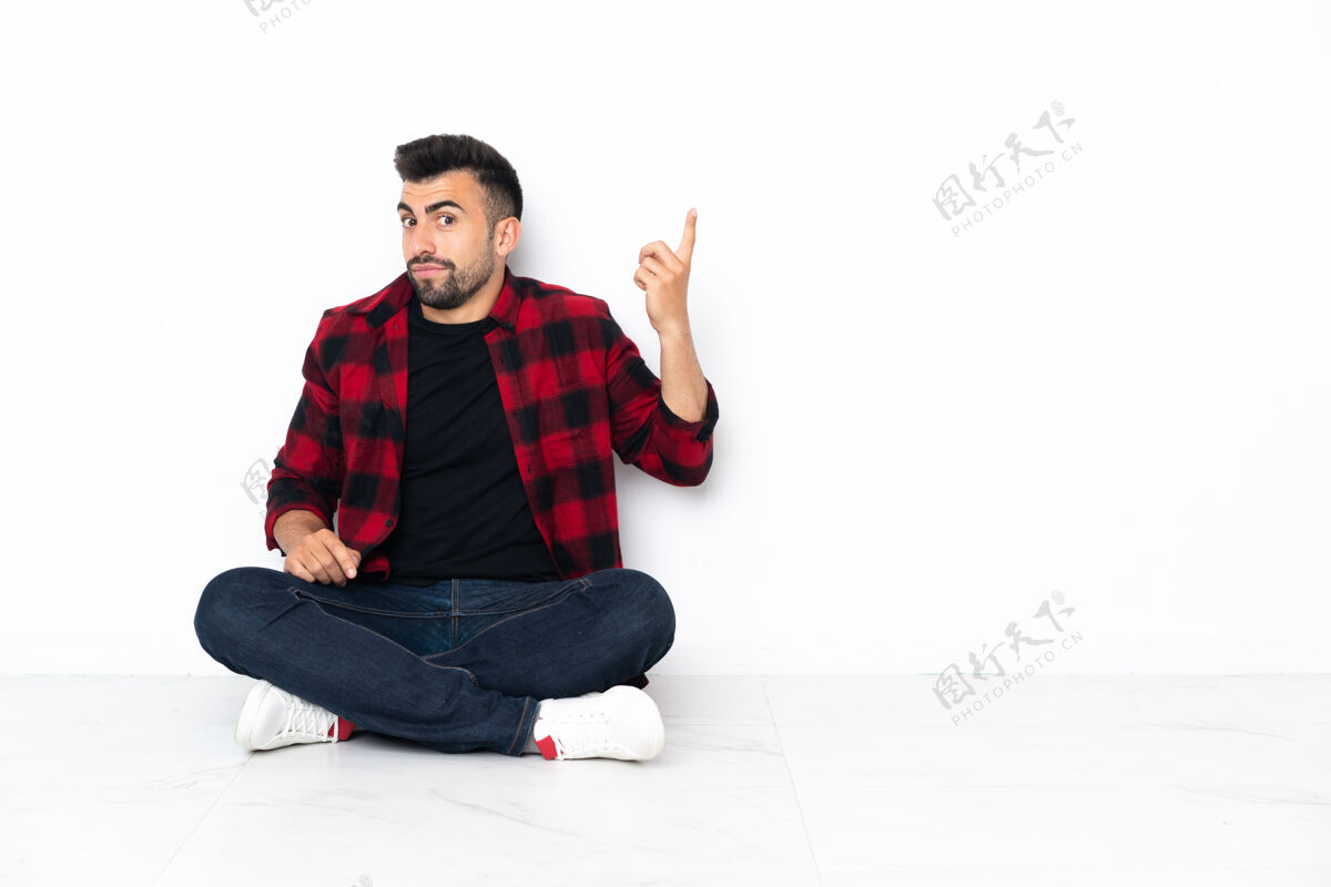 手指年轻帅哥坐在地板上用食指指指一个好主意身体拉丁语男性
