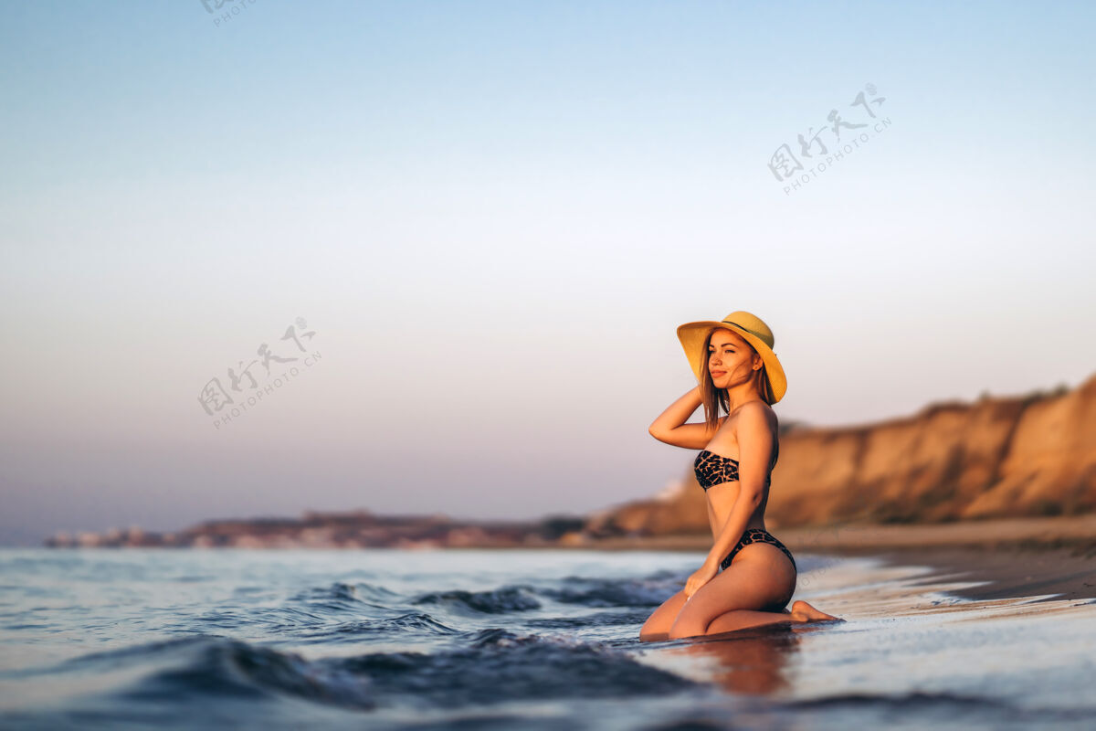 旅游漂亮的黑发女人在海边的海滩上放松时尚海浪帽子