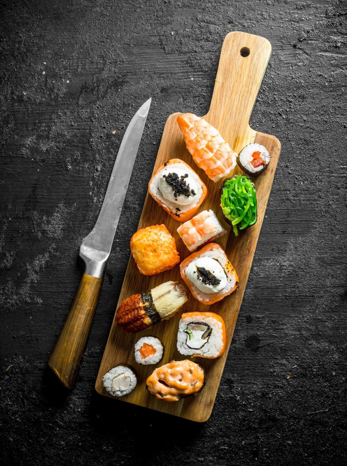 金枪鱼寿司卷上有虾 蔬菜和鲑鱼 用刀放在砧板上寿司套餐虾