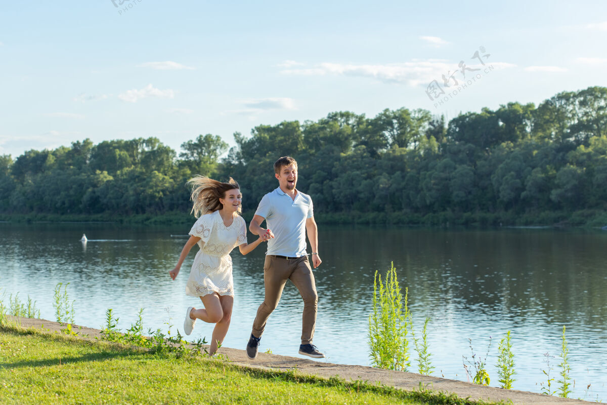 情侣爱情和关系概念-快乐的男人和女人在湖边的公园里奔跑爱河流水