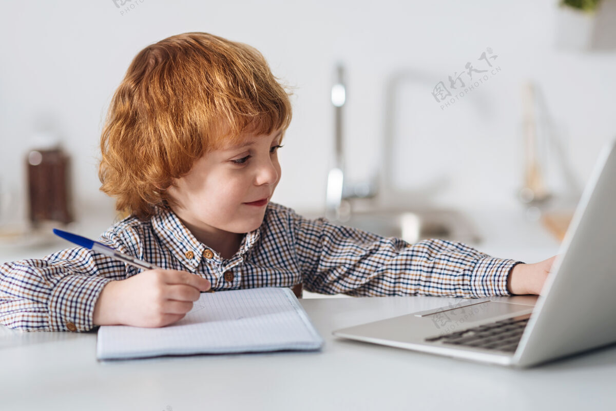世代准备为主武器承诺聪明聪明的孩子坐在厨房的桌子旁看书 做笔记智力科技早晨