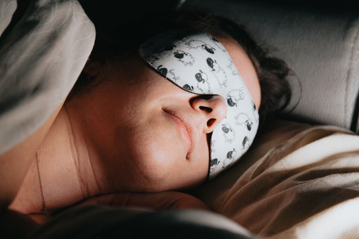 床一个女人睡觉的特写镜头 用羊皮做的睡眠面罩 脸上有亮光睡眠女人表情