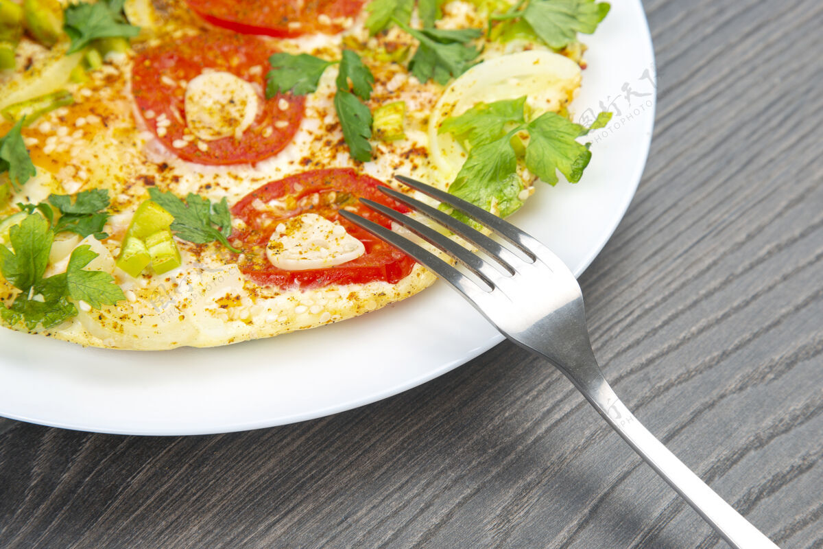 素食在木桌上的白色盘子里放着香草和蔬菜的煎蛋卷菜烘焙美味