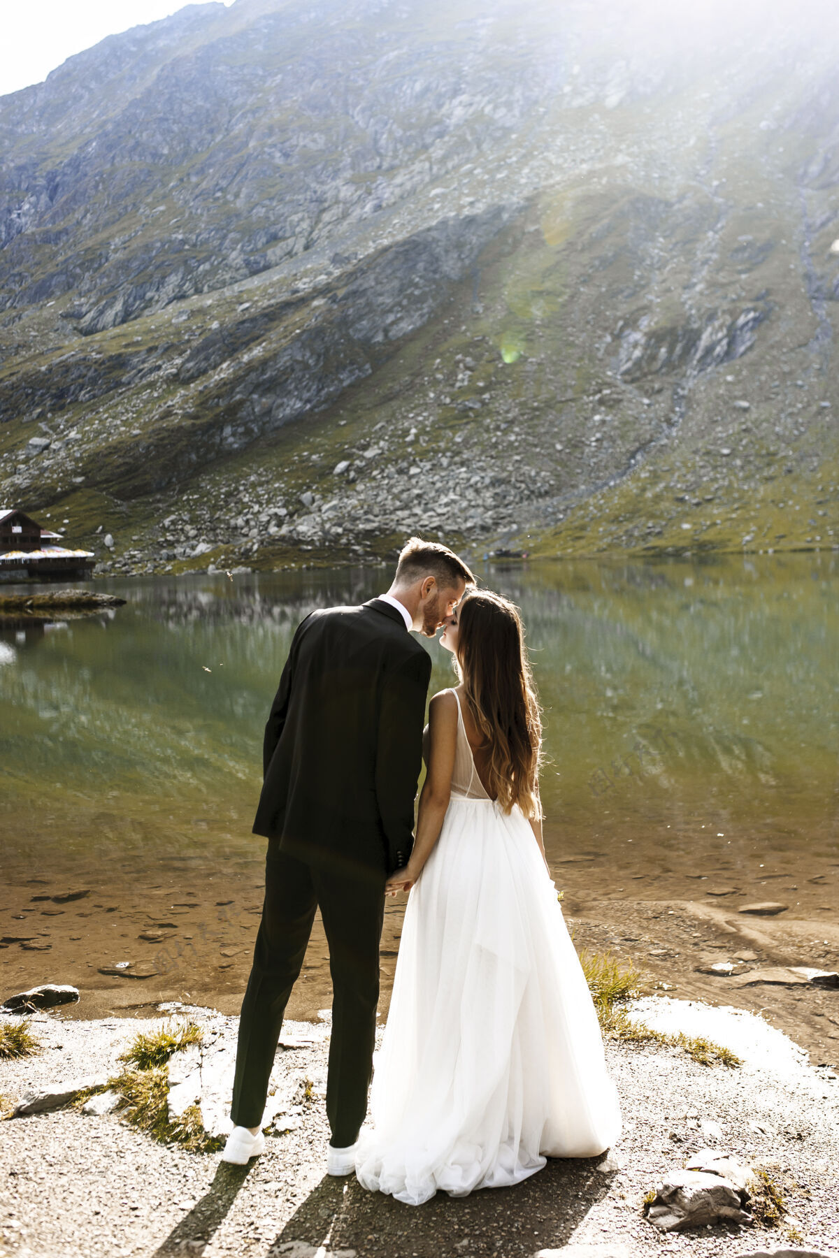 风景一个令人惊奇的新郎和新娘在山上的湖边接吻的完整长度山浪漫亲吻