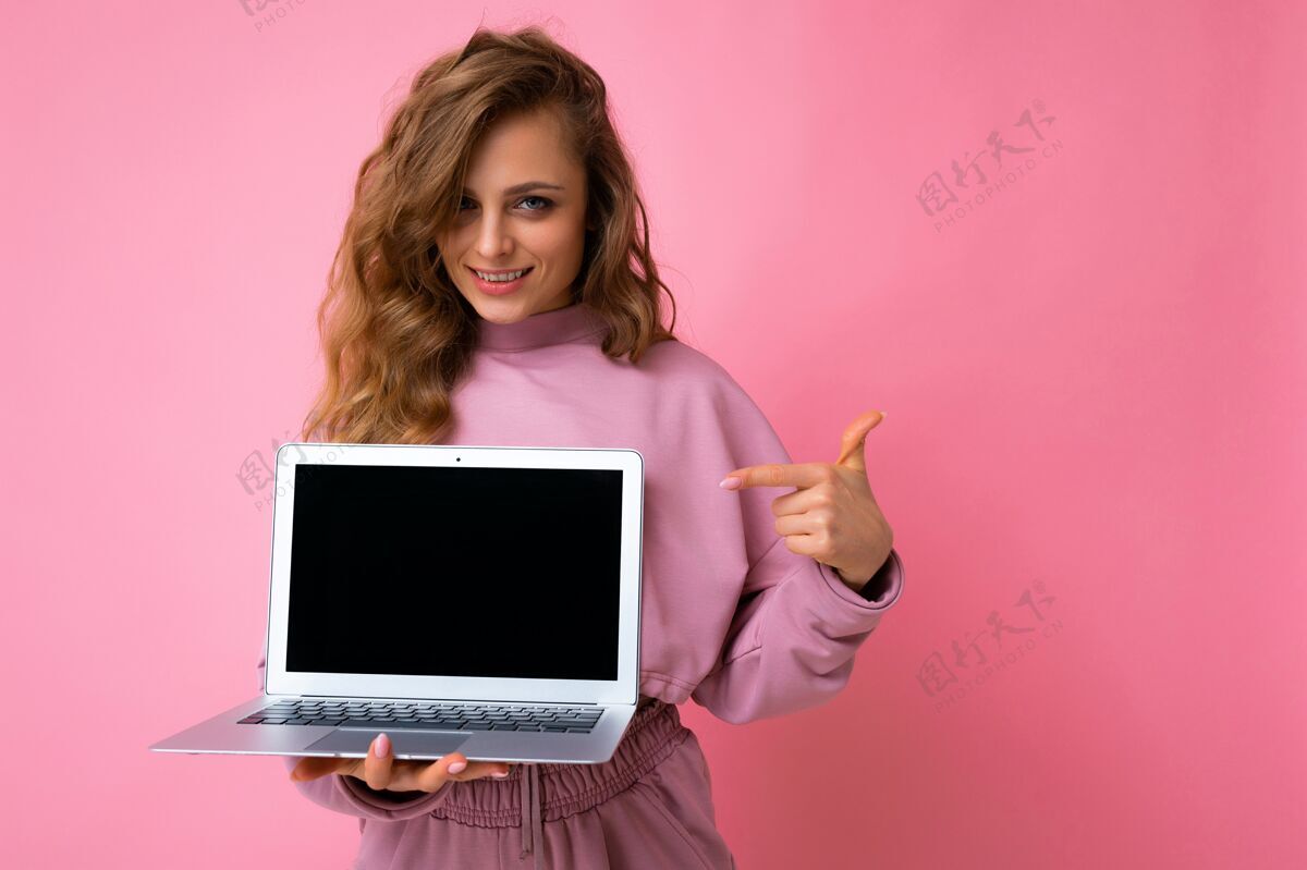 电脑美丽的金发卷发的年轻女子手里拿着空着的笔记本电脑便携式无线显示器