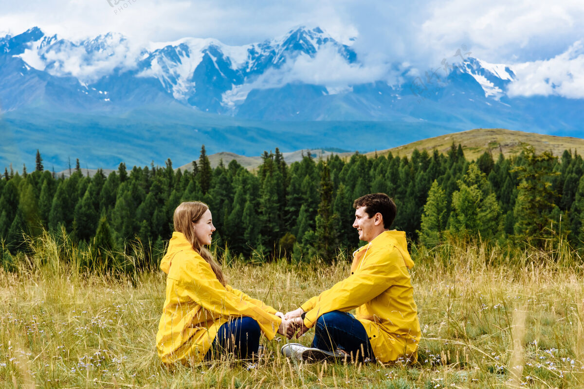 山丘远足的男人和女人手牵着手坐在阿尔卑斯山脉的背景下度假旅行自然山男性