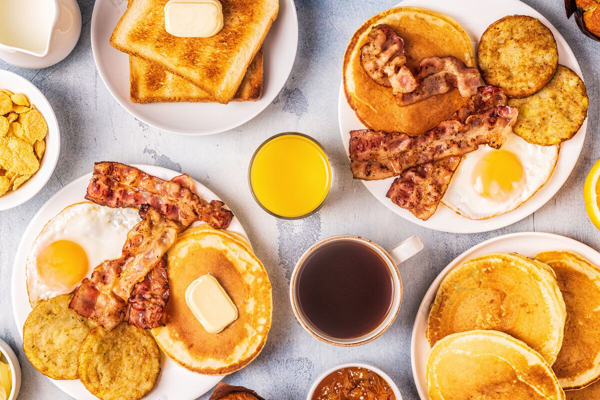 全套健康的美式早餐 有鸡蛋 培根 煎饼和拿铁 俯瞰美景黄油美式杯子
