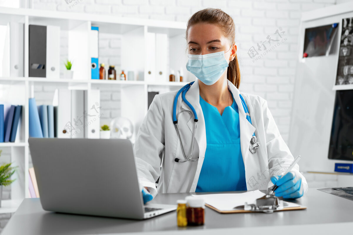 计算机年轻的女医生坐在工作台上用笔记本电脑医院医疗专业人员