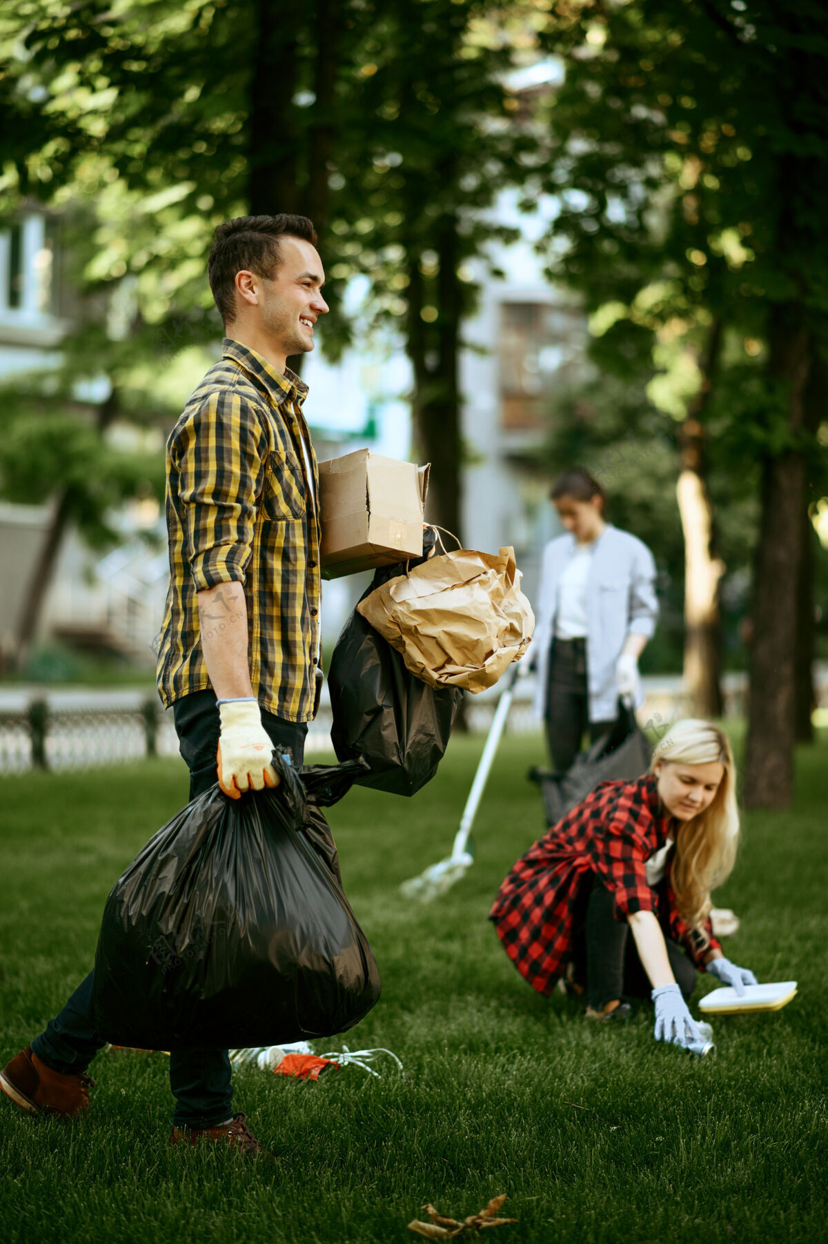污染年轻人在公园里拿着塑料垃圾袋 志愿服务男人清洁森林 生态恢复 生态生活方式 垃圾收集和回收公园手套环境