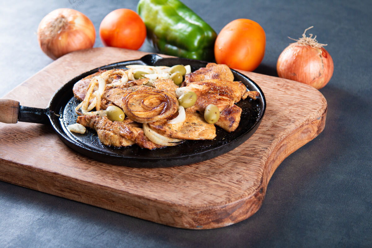 烹饪铁板上放着洋葱和橄榄的烤鸡烧烤晚餐切片