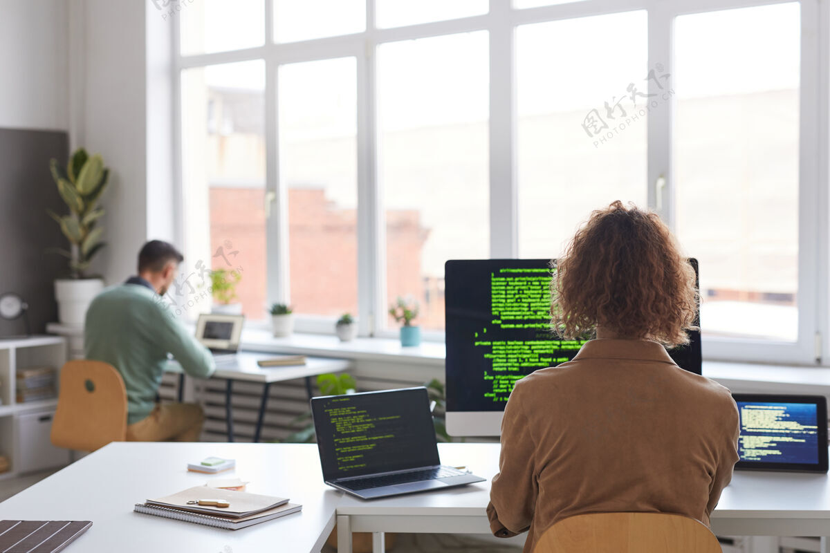 桌子在办公桌旁的电脑上使用新软件的人的后视图休闲服个人电脑商务女性