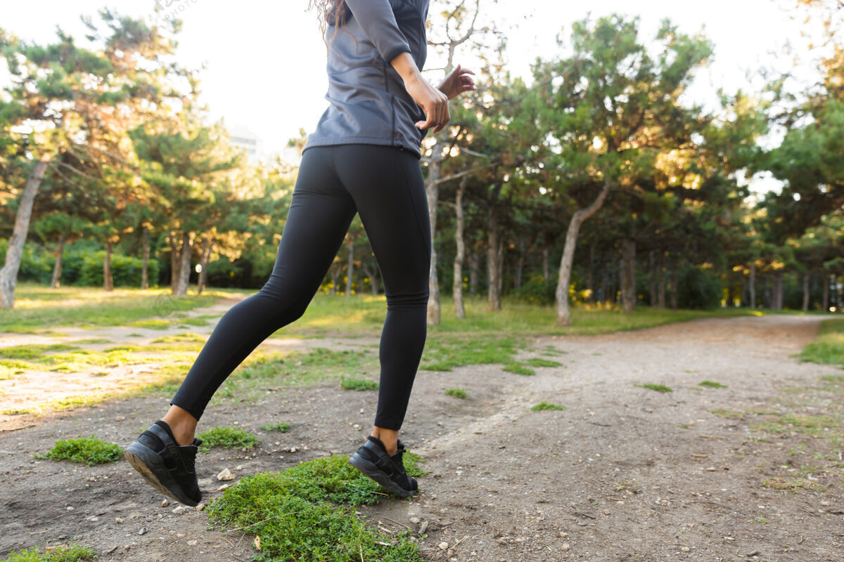 训练20多岁的瘦瘦的非洲裔美国女人穿着黑色运动服 在绿色公园里奔跑女性黑发女孩