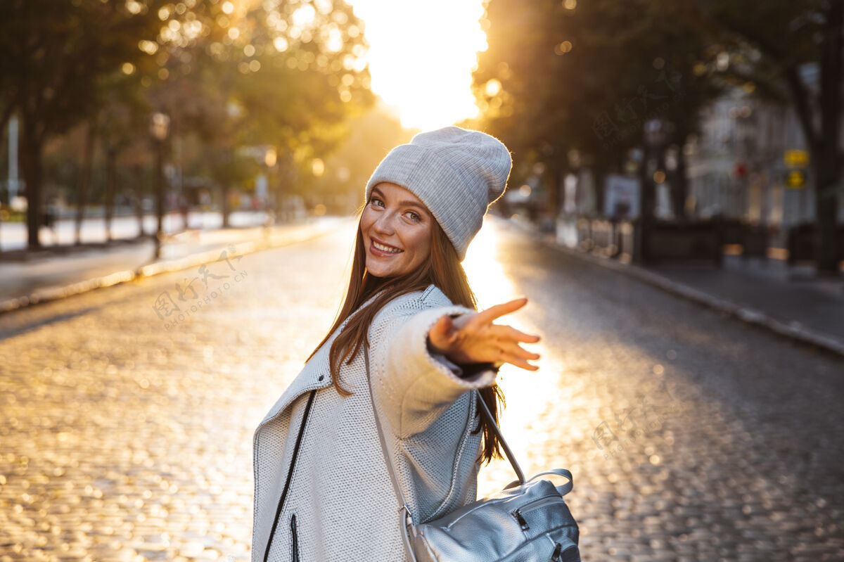 城市一个穿着秋衣 头戴秋帽 在城市街道上走在户外的快乐的年轻女子漂亮年轻自然