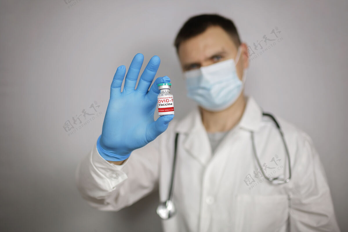剂量医生戴着医用口罩和手套 拿着装有冠状病毒疫苗的安瓿和注射器瓶子病毒疫苗