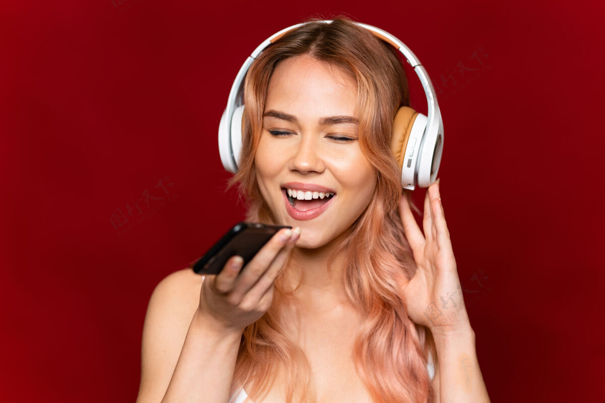 女人十几岁的女孩 一头粉红的头发 孤零零地听着红色的音乐 带着手机唱歌歌手表演歌曲