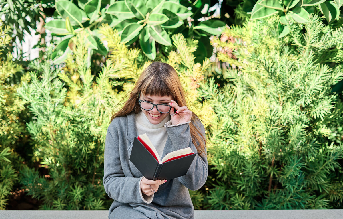 阅读一个蓝眼睛的白人金发女郎戴着眼镜在公园看书女孩金发女性