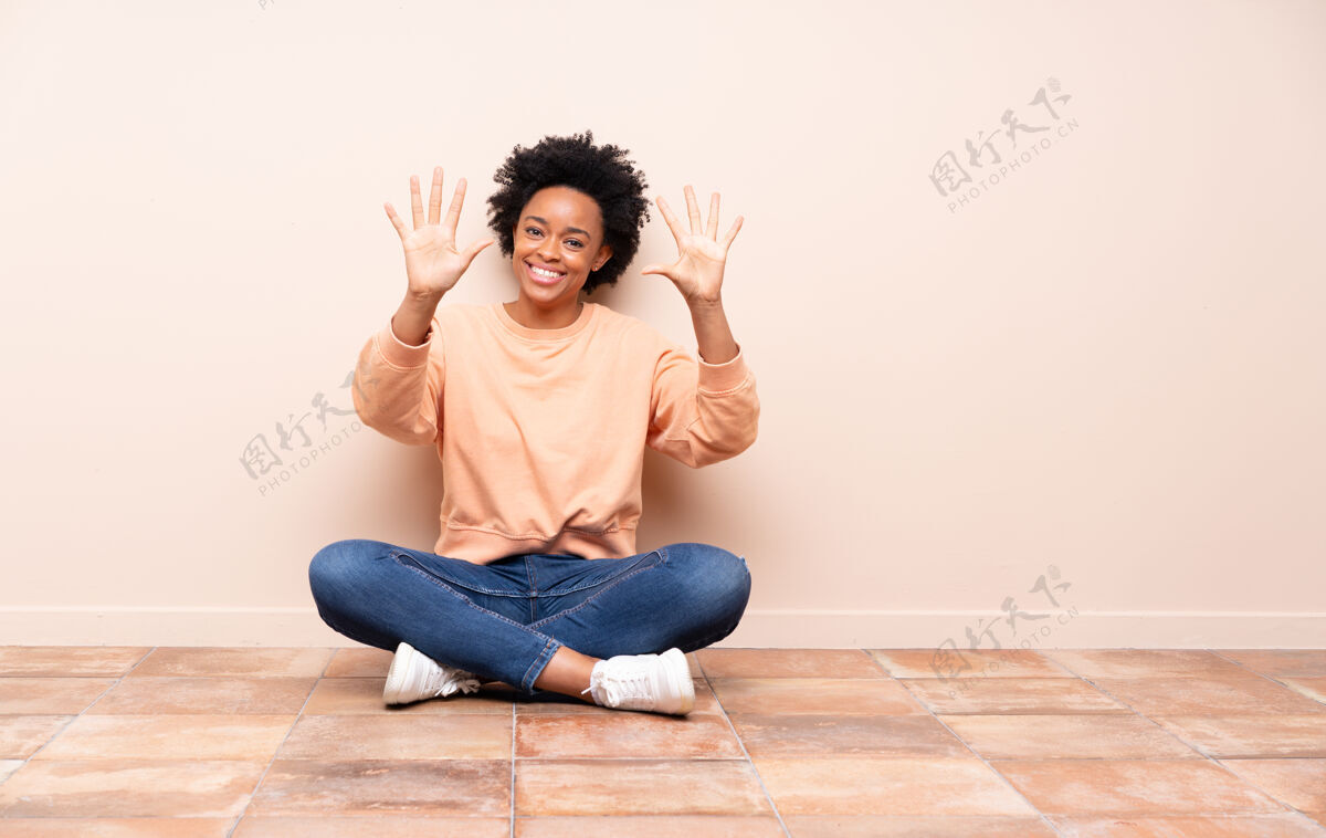 人坐在地板上用手指数十的非裔美国妇女室内成人女人
