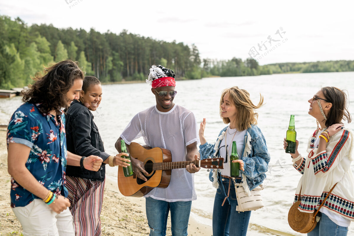音乐一群积极的年轻多民族朋友在嬉皮士黑人的吉他音乐下在沙滩上跳舞年轻人享受休闲活动