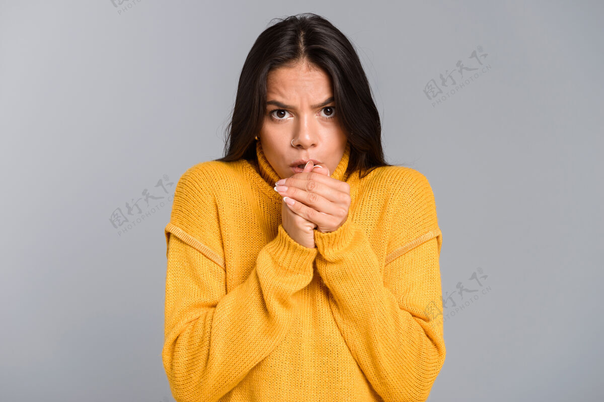 女士一个穿着毛衣的冻僵的年轻女子孤立地站在灰色的墙上 暖手的画像套装冰冻女人