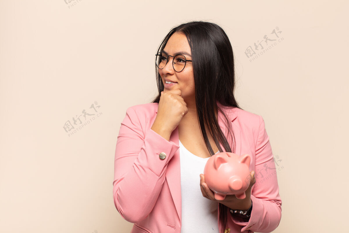 财务年轻的拉丁女子微笑着 手放在下巴上 脸上洋溢着幸福 自信的表情 一边疑惑 一边看着身边人银行看