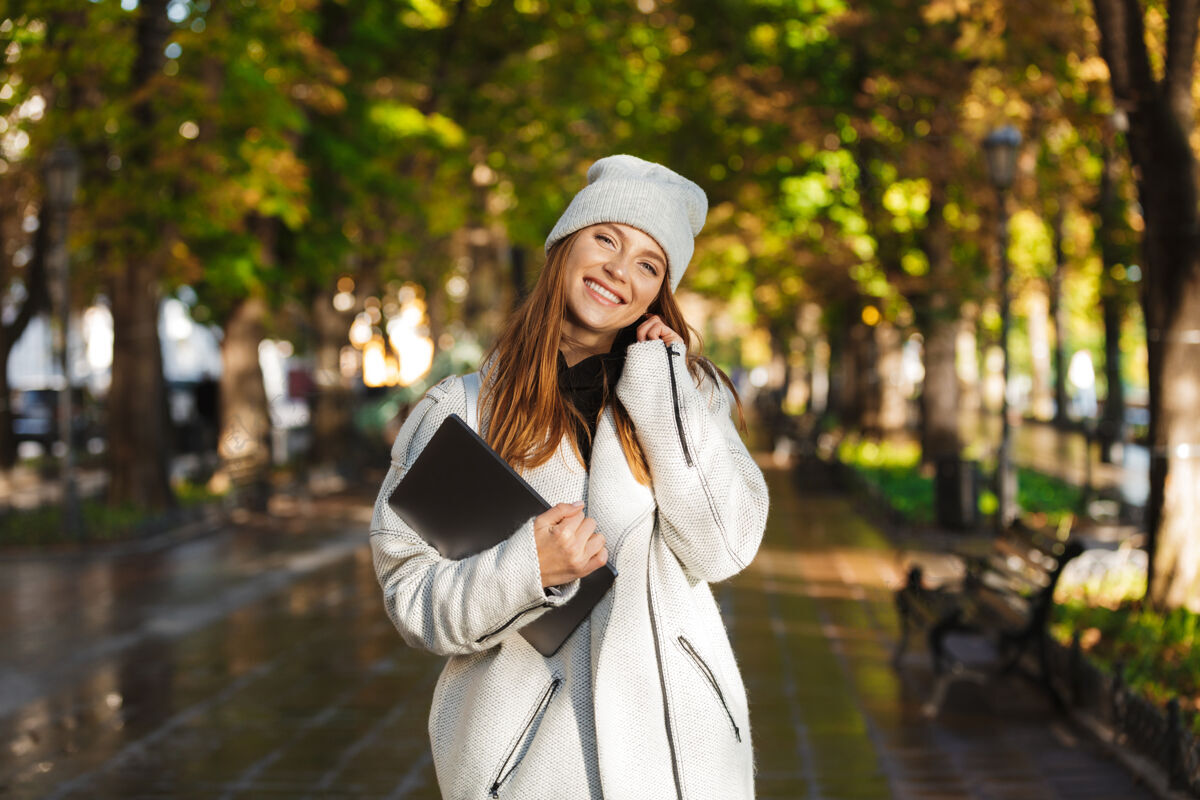 城市照片中 一个红发快乐的女人走在街上 微笑着开着笔记本电脑成人休闲时尚