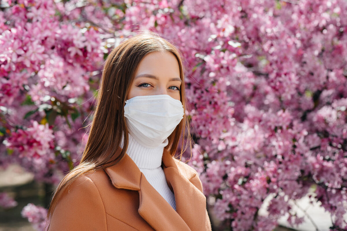 安全在一个阳光明媚的春日 在盛开的花园前 一个小女孩摘下口罩 深呼吸着流感大流行结束后的气息花病毒温暖