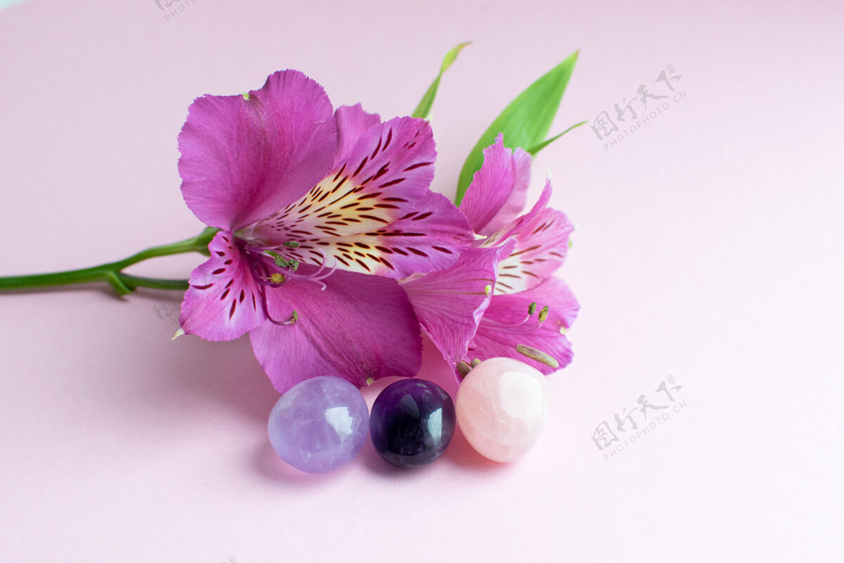 钻石粉色表面上的亮粉色花 以及紫晶和玫瑰石英的矿物颜色水晶Alstroemeria