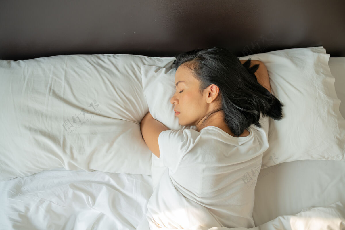 早晨宁静的年轻女士穿着睡衣躺在床上睡着了顶视图床女性躺下
