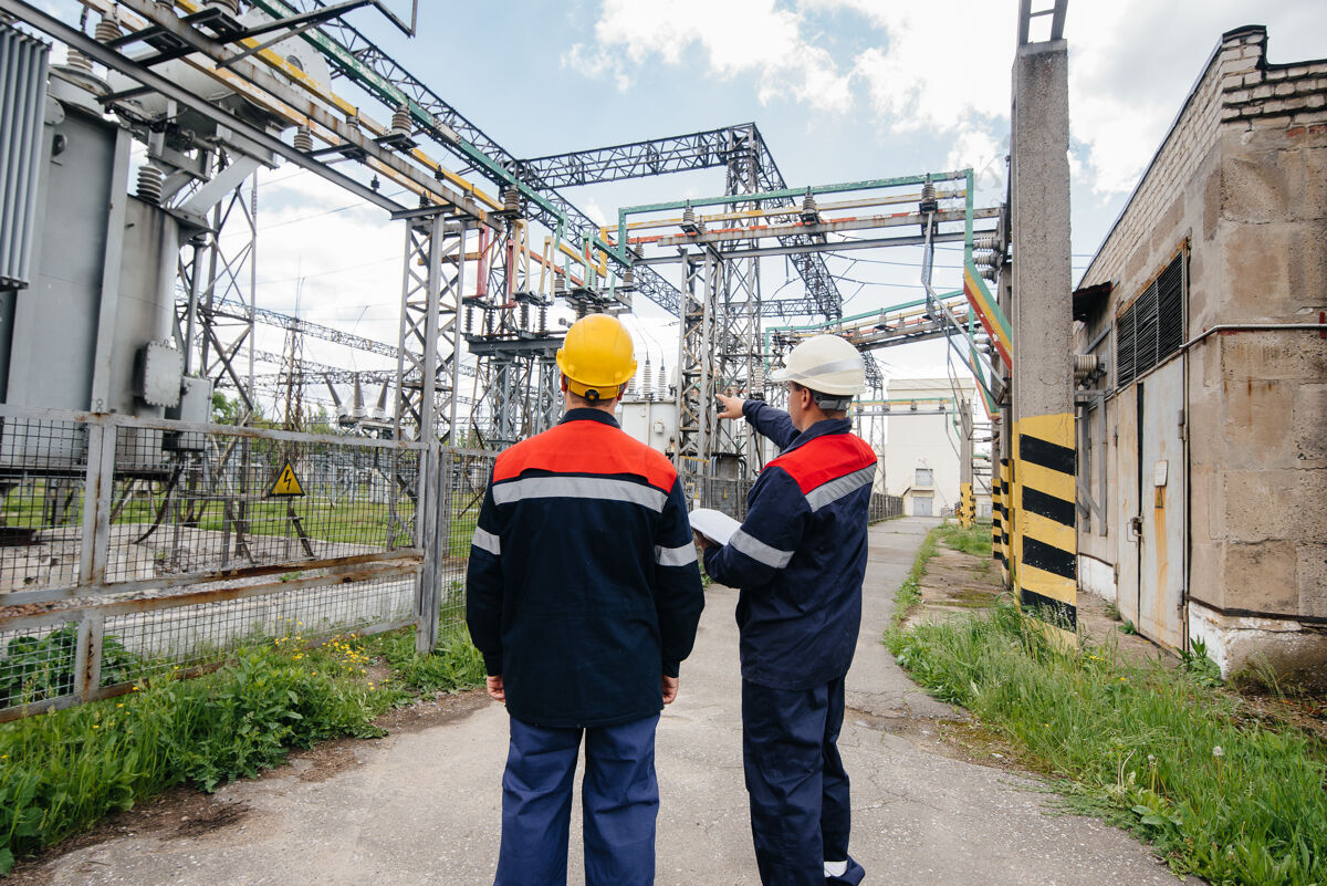 头盔两名专业变电站工程师检查现代高压设备能源工业安全恢复能源
