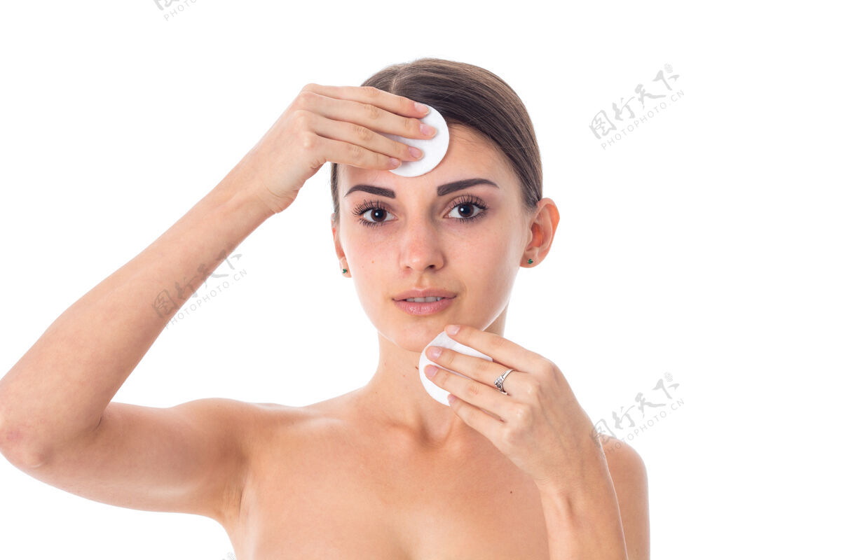 漂亮性感的年轻女子用隔离在白墙上的清洁棉来护理她的皮肤Spa护理日本人