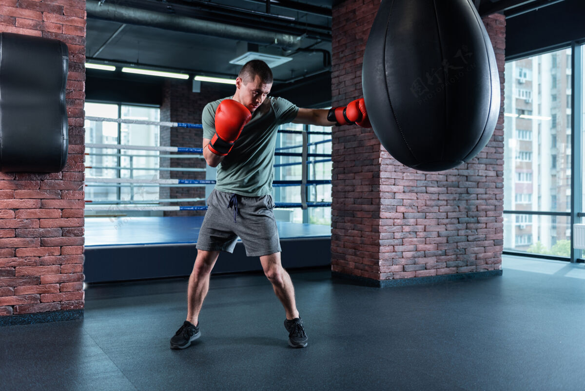 动作拳击硬强壮的专业技术运动员穿着灰色短裤和卡其色衬衫拳击硬戴红色手套压力运动偏见