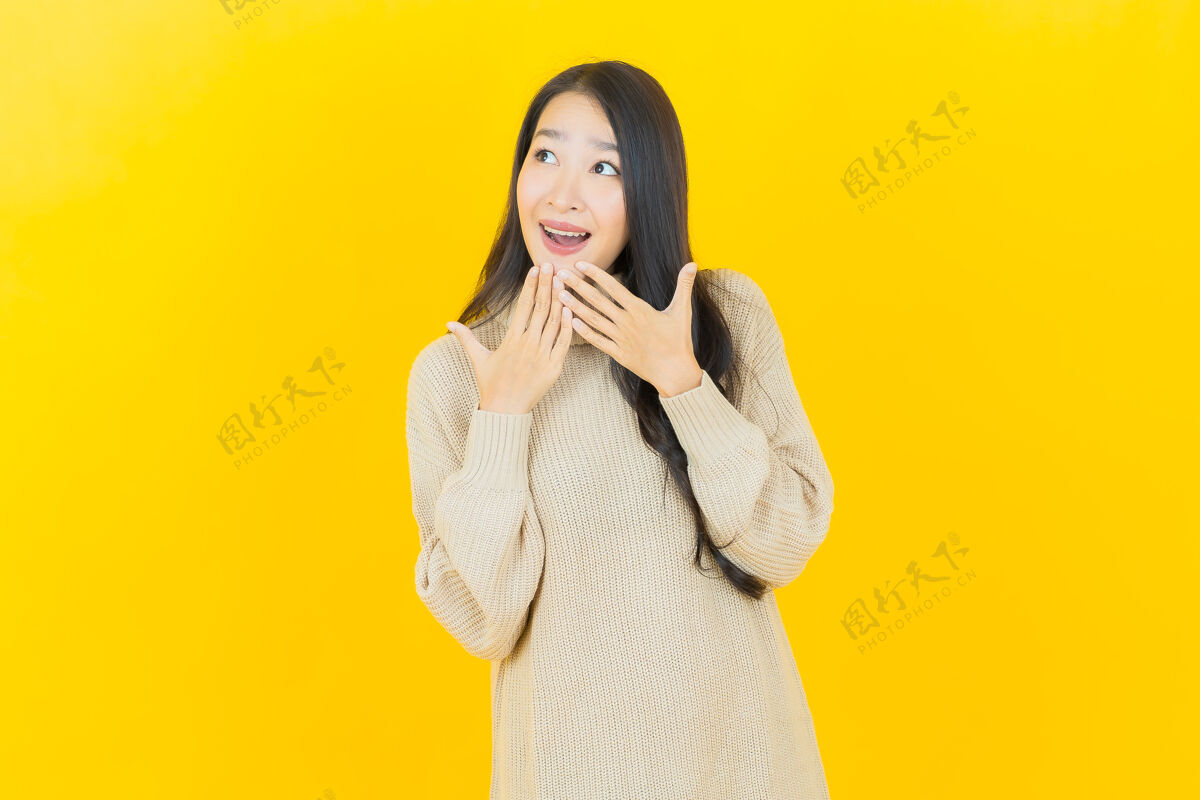 女人美丽的亚洲年轻女子在黄色的墙上微笑成人时尚头发