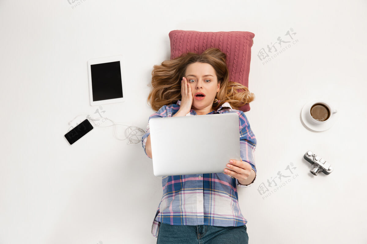 顶视图年轻的白人妇女使用笔记本电脑和红枕头手指技术现代