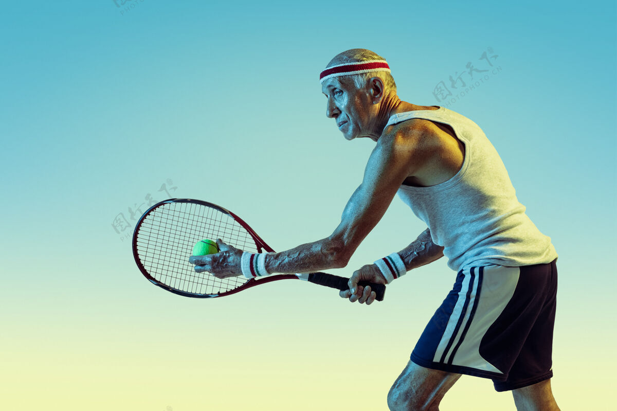 运动员穿运动服的高级男士在梯度背景下打网球 霓虹灯身材魁梧的白种男性模特保持活跃 运动运动的概念 活动 运动 健康 自信健康微笑比赛