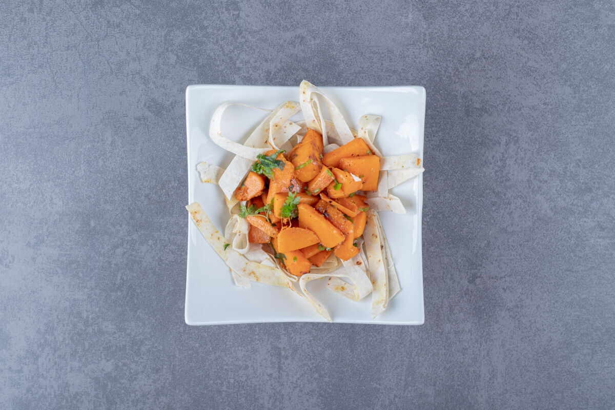 盘子把烤胡萝卜和拉瓦什片放在碗里 放在大理石表面美味切片新鲜