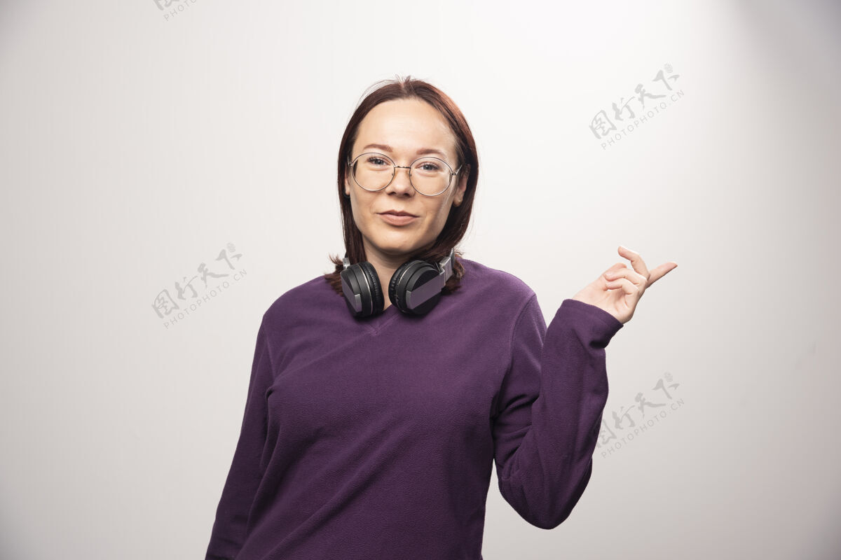 肖像戴着眼镜的年轻女子戴着耳机摆出一张高质量的白色照片年轻女士青春