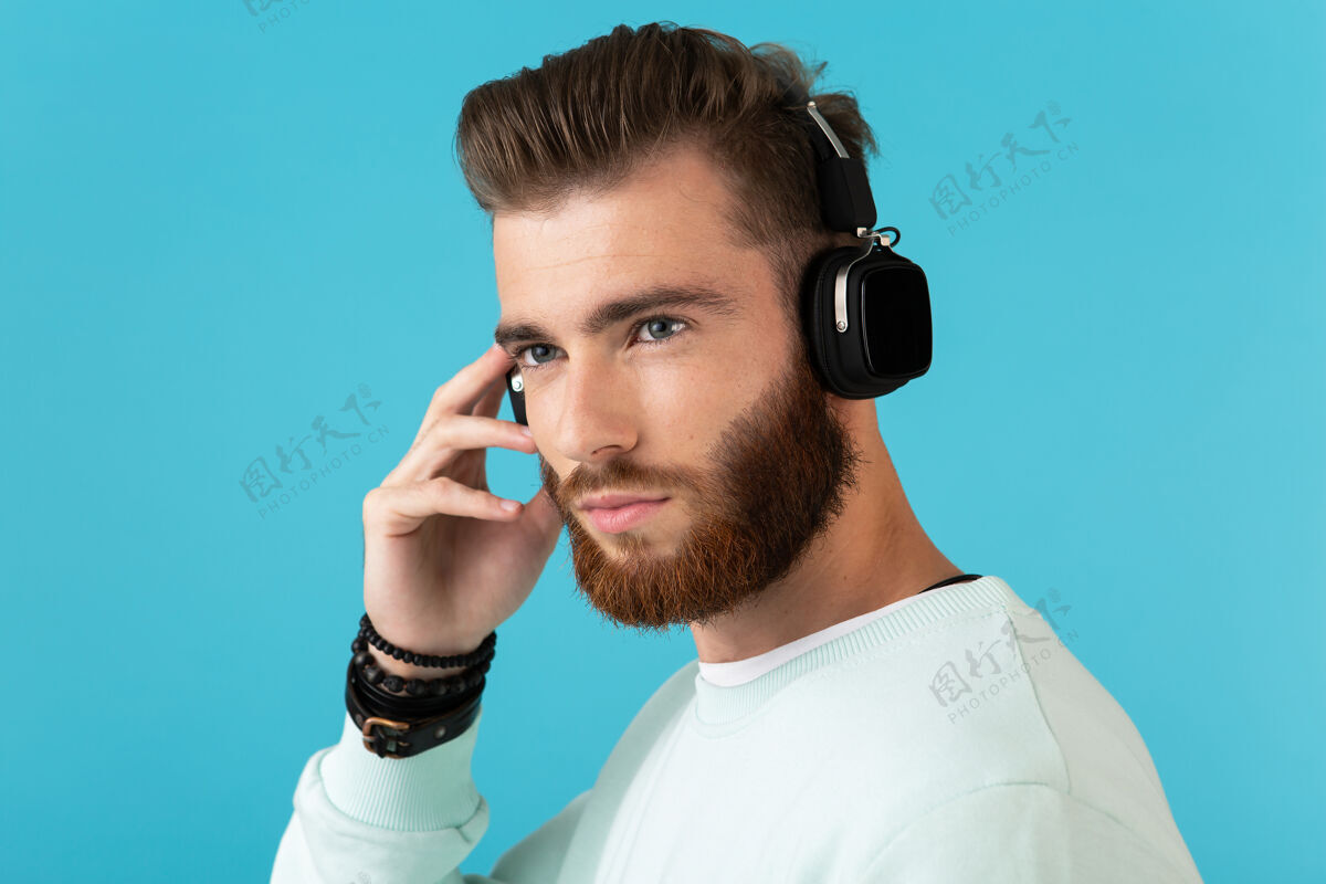 声音时尚迷人的年轻留胡子的男人在无线耳机上听音乐的肖像现代风格自信的心情胡须酷音频