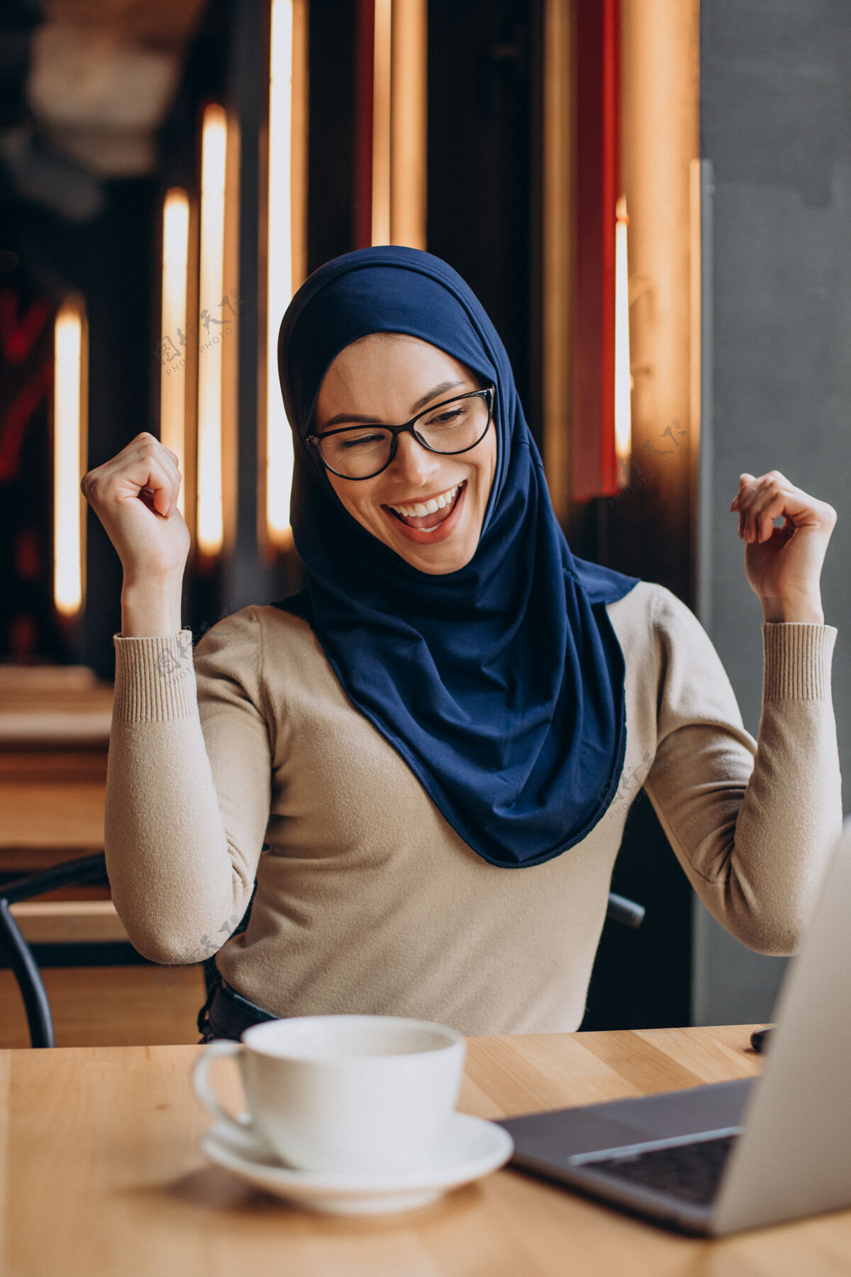 穆斯林在咖啡馆里用电脑上网的年轻女青年女性伊斯兰情感